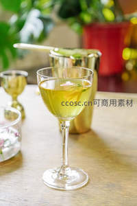 金绿色鸡尾酒特写，花瓣点缀，金属调酒壶背景温馨
