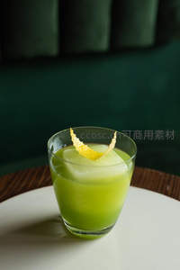青苹果风味鸡尾酒：大冰块与柠檬皮卷装饰短杯