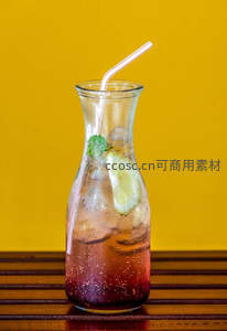 玻璃醒酒壶装气泡饮料，青柠薄荷配吸管，黄墙背景