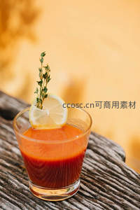木质台面上的番茄汁特写，暖光映衬柠檬与香草装饰