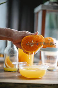 手挤橙子滴汁入量杯，厨房台面展现鲜榨果汁制作过程