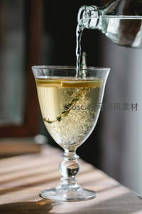 气泡水注入高脚杯，柠檬片与迷迭香在光线下跃动