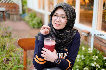 戴头巾女子户外品饮红色冰沙，惬意午后咖啡时光