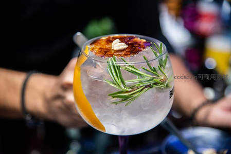 特写调酒师手持焦糖布蕾装饰金汤力，迷迭香与橙皮增添风味层次