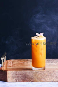 橙色冰饮置于木质托盘，烟雾缭绕，花瓣点缀清新雅致