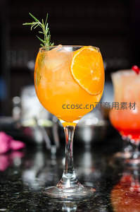 橙香鸡尾酒配迷迭香与橙片，吧台光影映衬晶莹冰块