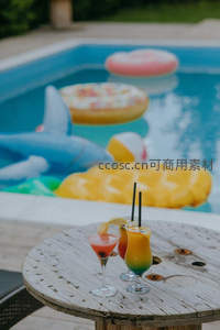 泳池派对彩色鸡尾酒与充气玩具，木质圆桌上的夏日欢乐时光