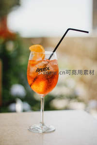 阿佩罗橙光气泡酒特写，黑吸管与橙片点缀高脚杯中的意式风情
