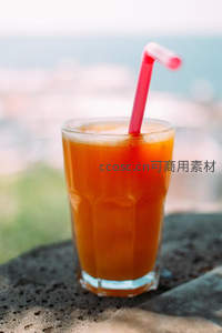 海景露台橙汁特写，红色吸管插于冰爽果汁杯中