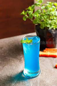亮蓝色薄荷冰饮特写，背景绿植与胡萝卜增添活力健康感