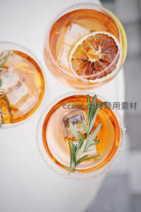 三杯橙色气泡饮品俯拍，饰以柠檬片与迷迭香，冰块晶莹剔透
