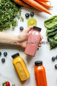 手握草莓胡萝卜汁，周围环绕多种果蔬原料