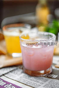 盐边粉红鸡尾酒与啤酒杯置于报纸上的微距静物
