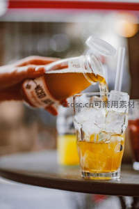 手倒瓶装茶饮入冰块玻璃杯动态瞬间