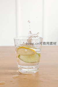 柠檬青柠入水瞬间抓拍，飞溅水珠定格动感，木质桌面简约清新