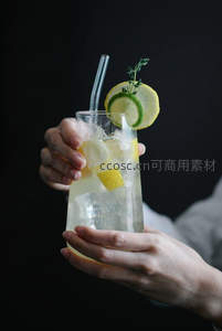 黑背景下双手捧持柠檬青柠苏打水特写