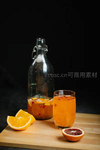 血橙苏打水配玻璃瓶装果茶，木质台面呈现简约高对比度构图