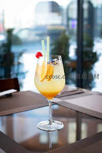 金黄柠檬气泡酒配双吸管与樱桃装饰，窗边餐桌倒影映现都市水景