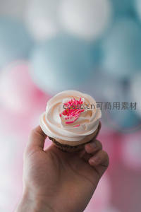 手持玫瑰奶油纸杯蛋糕，背景梦幻气球光斑