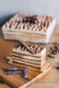 经典提拉米苏切片特写，层次分明奶油与手指饼干，木板上巧克力碎点缀