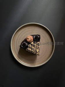 黑底陶盘上的巧克力千层蛋糕切片，费列罗与巧克力酱装饰