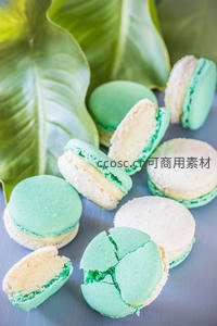 薄荷绿马卡龙切开展示夹心，搭配热带绿叶背景清新雅致