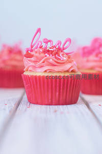 粉色情人节纸杯蛋糕特写，'love'糖艺字样与心形糖珠点缀浪漫氛围