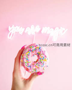 手举粉色糖霜甜甜圈，背景霓虹灯语'you are magic'