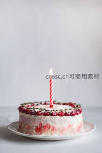 单支红白条纹蜡烛插于蔓越莓装饰蛋糕，简约温馨生日场景