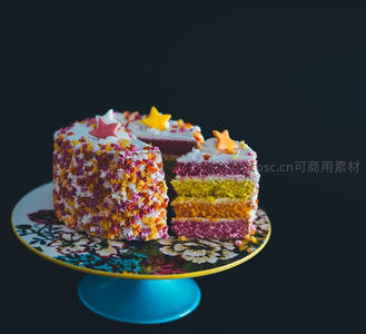 彩虹分层裸蛋糕切开展示，彩色糖珠星形装饰黑底特写