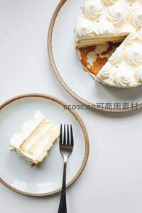 简约白奶油蛋糕切片，陶瓷盘与金属叉的静谧美食构图