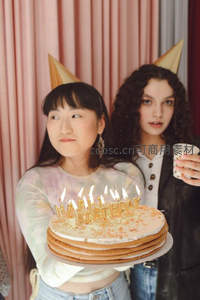 两位女孩举着生日蛋糕合影，派对欢乐瞬间