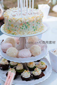 三层甜品架摆生日蛋糕与马卡龙纸杯蛋糕，彩糖珠点缀，户外派对场景