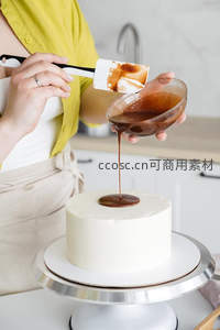 厨师正将温热巧克力酱缓缓浇淋在洁白蛋糕顶面，动作专注优雅