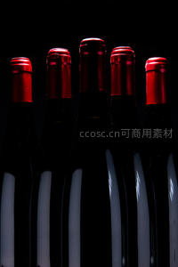暗调光影下五支红酒瓶排列，红箔封口反光质感突出