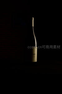 昏暗砖墙前单支干白葡萄酒瓶，标签微光聚焦