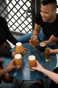 朋友围坐蓝桌举杯畅饮精酿啤酒，笑容洋溢夏日午后