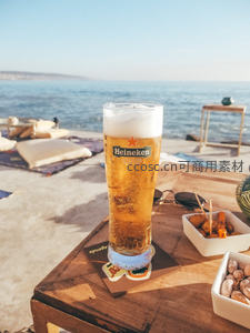 海边木桌上的冰镇喜力啤酒与小食，阳光明媚度假氛围