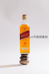 尊尼获加红牌威士忌平衡于三块叠石之上，极简主义静物构图