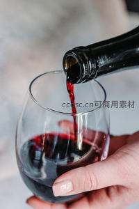红酒倾倒入高脚杯瞬间特写，手部细节与液体动态展现优雅品酒时刻
