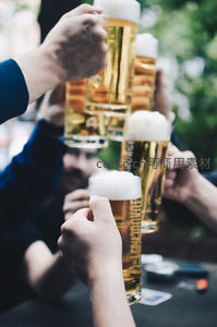 多人围桌举杯欢庆，金黄啤酒泡沫翻涌的热闹聚会场景