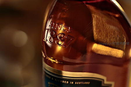 琥珀色酒瓶特写，'SINCE 1887'浮雕铭文在暖光下熠熠生辉