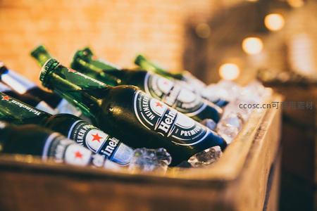 冰桶中堆叠的喜力啤酒绿瓶，冷凝水珠与暖光形成冷暖对比