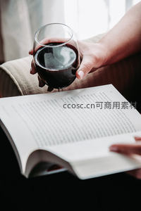 手持红酒杯静读时光，深红液体映衬书页文字的宁静午后