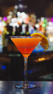 橙色鸡尾酒盛于马天尼杯，饰以橙片，酒吧霓虹光斑背景梦幻迷离