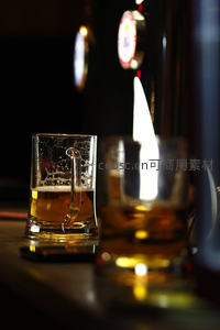 酒吧吧台特写：扎啤杯盛满金黄啤酒，酒头正在倾倒液体
