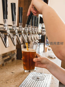 吧台特写：金黄啤酒正从龙头注入透明玻璃杯，泡沫细腻升腾