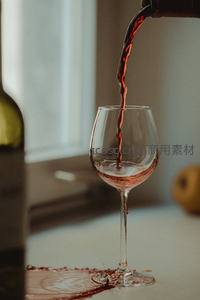 红酒倾倒入高脚杯瞬间，酒液飞溅形成动态弧线，桌面微溢洒显真实感