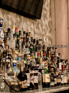 酒吧吧台琳琅满目酒瓶陈列，复古瓷砖墙与电视屏幕映衬专业调酒环境