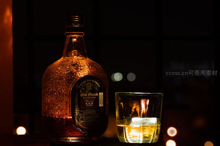 老朗姆酒夜景特写：暖光映照雕花瓶身与冰块威士忌